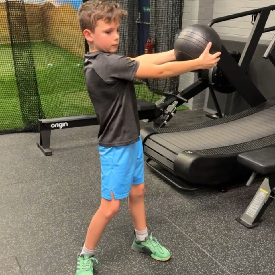 Junior athlete holding a medicine ball and rotating for a core strength drill
