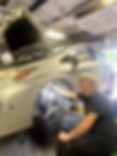 Mechanic in a cowboy hat working on a car wheel well