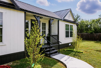 White farmhouse-style home with black trim, steps, and porch