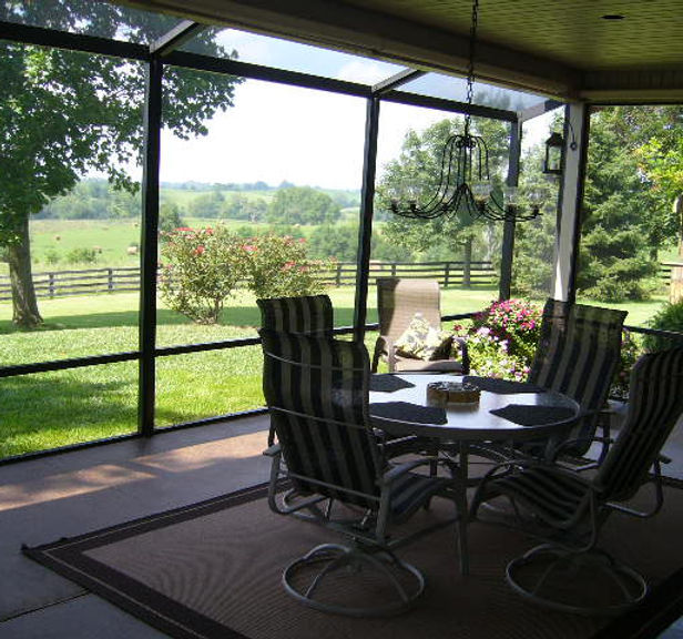 Screened porch with patio furniture overlooking a scenic landscape