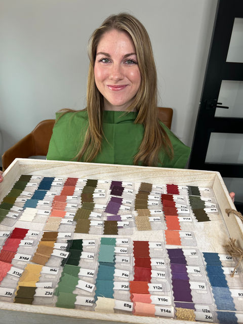 Smiling woman displays tray of colorful fabric swatches