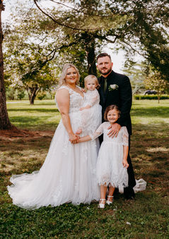 a bride and groom pose with their two daughters