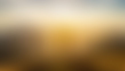 L’image montre une personne debout au sommet d’une montagne, les bras levés vers le ciel dans un geste de victoire ou de célébration. La silhouette est en contre-jour, entièrement noire, car le soleil se trouve directement derrière elle, créant un halo lumineux autour du corps et des rayons de lumière qui se diffusent dans toutes les directions. Le soleil est bas, probablement au lever ou au coucher, et inonde la scène d’une lumière dorée, qui éclaire les crêtes et les pentes des montagnes environnantes.