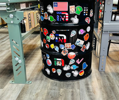 Black barrel covered in stickers, used as a counter