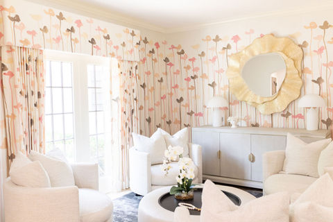 Bright and whimsical sitting room by Birdy Design featuring custom floral drapery, boucle swivel chairs, sculptural gold mirror, and soft neutral tones for a feminine, luxe interior.