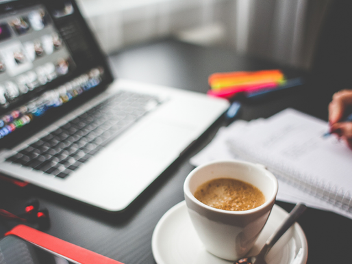 Creative workspace with coffee, a laptop open to a photo editor, and someone writing notes, reflecting the balance of creativity and strategy in content creation.