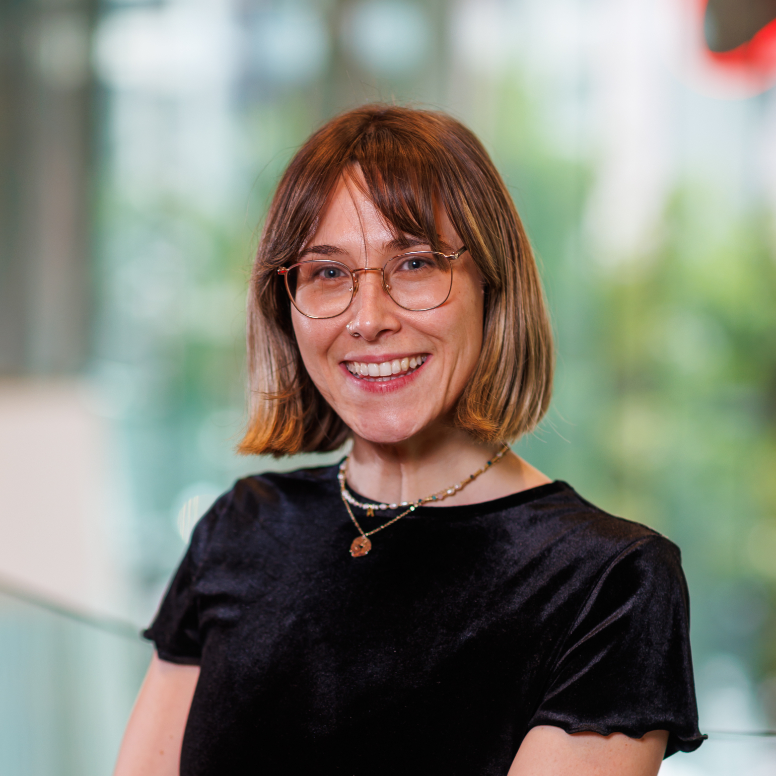Smiling woman with glasses wearing black top posing for a photo.