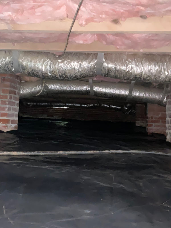 Crawl space with batt insulation and black 10-mil liner