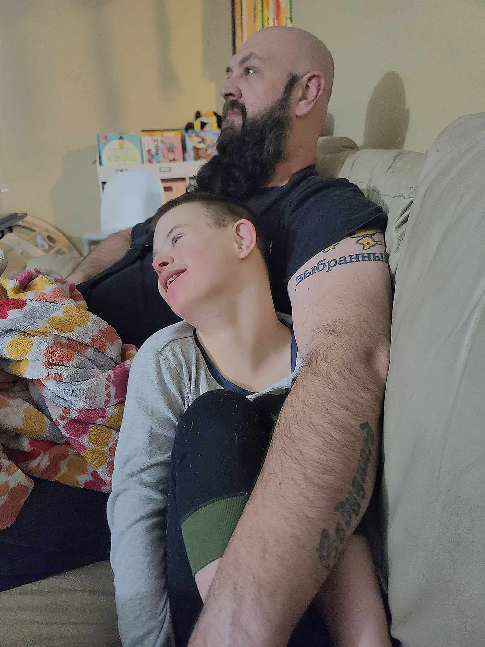 Jasper cuddling up with his dad on the couch, both looking relaxed and content as they enjoy a quiet moment together.