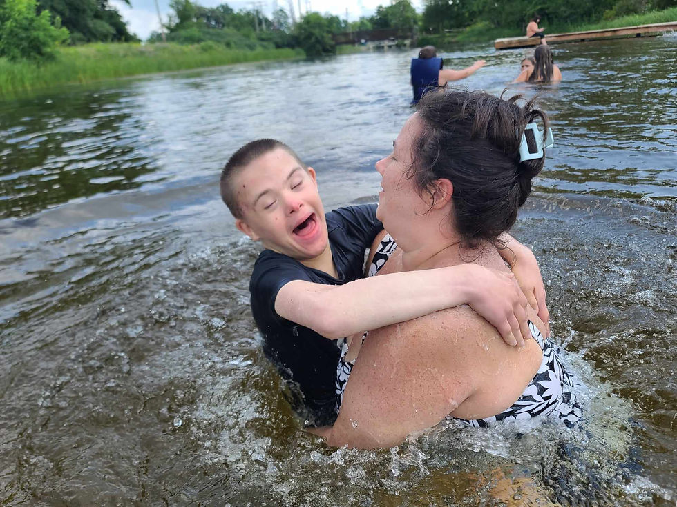 Jasper laughing joyfully while swimming in a river, held by his aunt as they enjoy a fun moment together in the water.