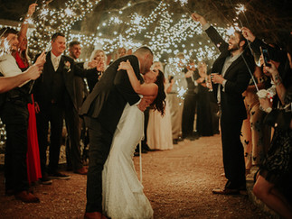 Bride and groom kissing during sparkler exit under twinkle lights at Benbrook Stables in Fort Worth, Texas
