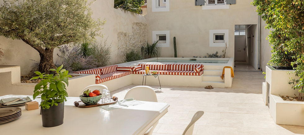 Rénovation haut de gamme d'une cour intérieure à Gruissan dans l'Aude,Occitanie, avec piscine, bassin, plages en béton ciré béton ciré, banquettes rayées Riviéra. Arbres : Olivier, cactus. So en travertin.