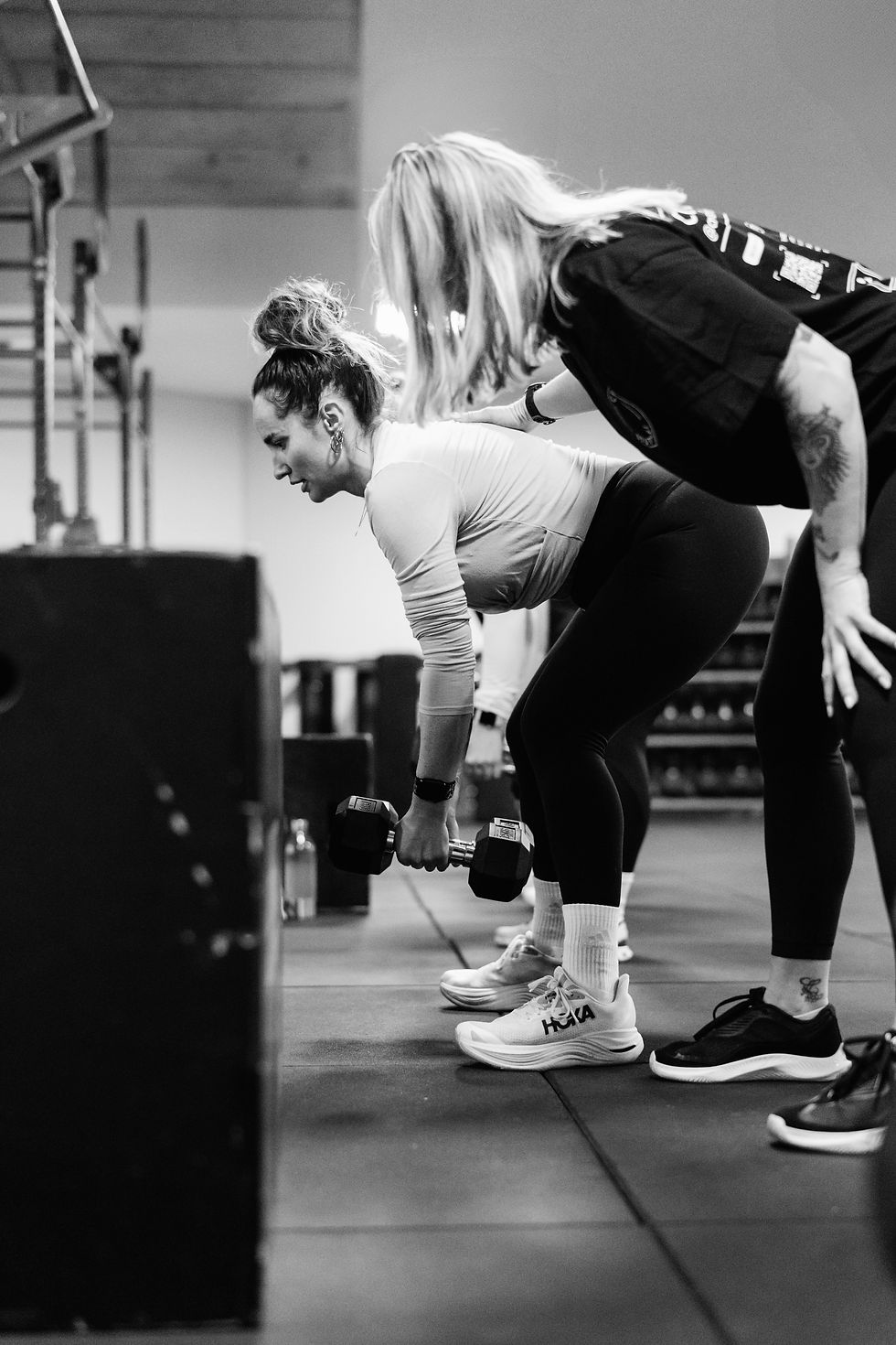 Coach guiding a member through a hinge movement next to a plyo box