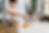Two children in safety goggles mix orange liquid in glass lab flasks at a white table in a bright room with plants