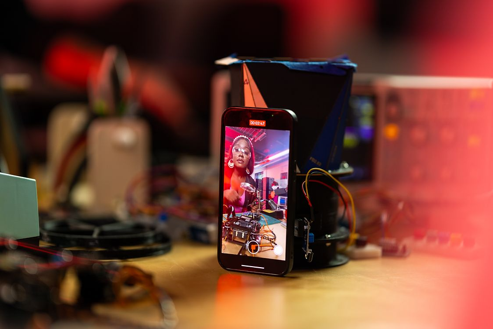 Smartphone on a workbench records a woman in a red top at an electronics setup, with wires and a 00:02:47 timer on screen.