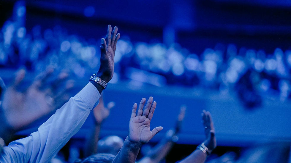 A vibrant concert audience captured with hands raised under dramatic blue lighting.