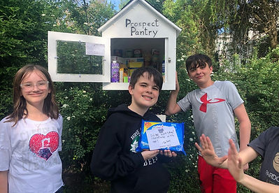 Photo of kids gathered around a Little Free Food Pantry in Medina holding a pack of oreos.