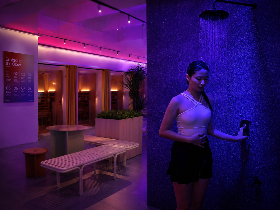 Woman taking a 6°C cold shower at Revibe Malaysia, with the infrared sauna lounge visible in the background
