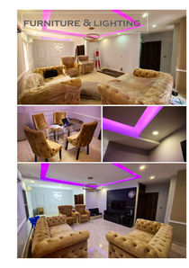 Modern living room with upholstered furniture and purple LED ceiling lighting.
