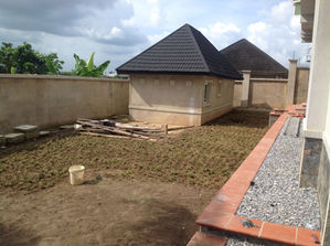 Small building with dark tiled roof in a partially prepared yard.