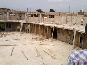 Circular concrete building under construction with many wooden support beams.