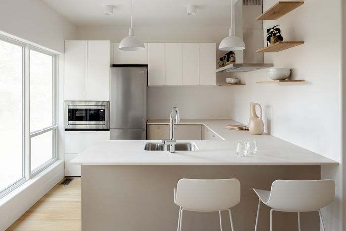 A kitchen front on with windows on the left, chairs on the right. By talented Vancouver Island Design Photographer Kyle Graham
