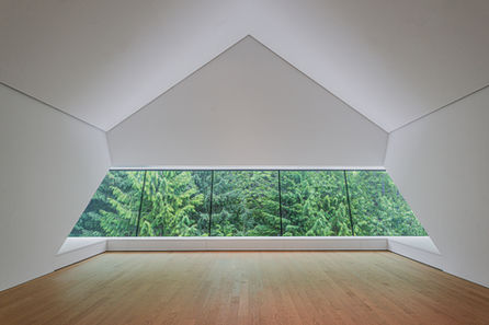 Patkau Architecture upper gallery space with a long window looking into the trees, wooden floors with a tall white ceiling 