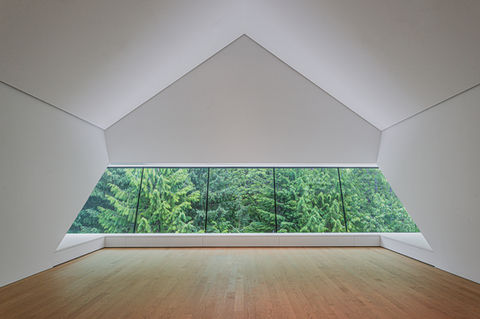 Patkau Architecture upper gallery space with a long window looking into the trees, wooden floors with a tall white ceiling 