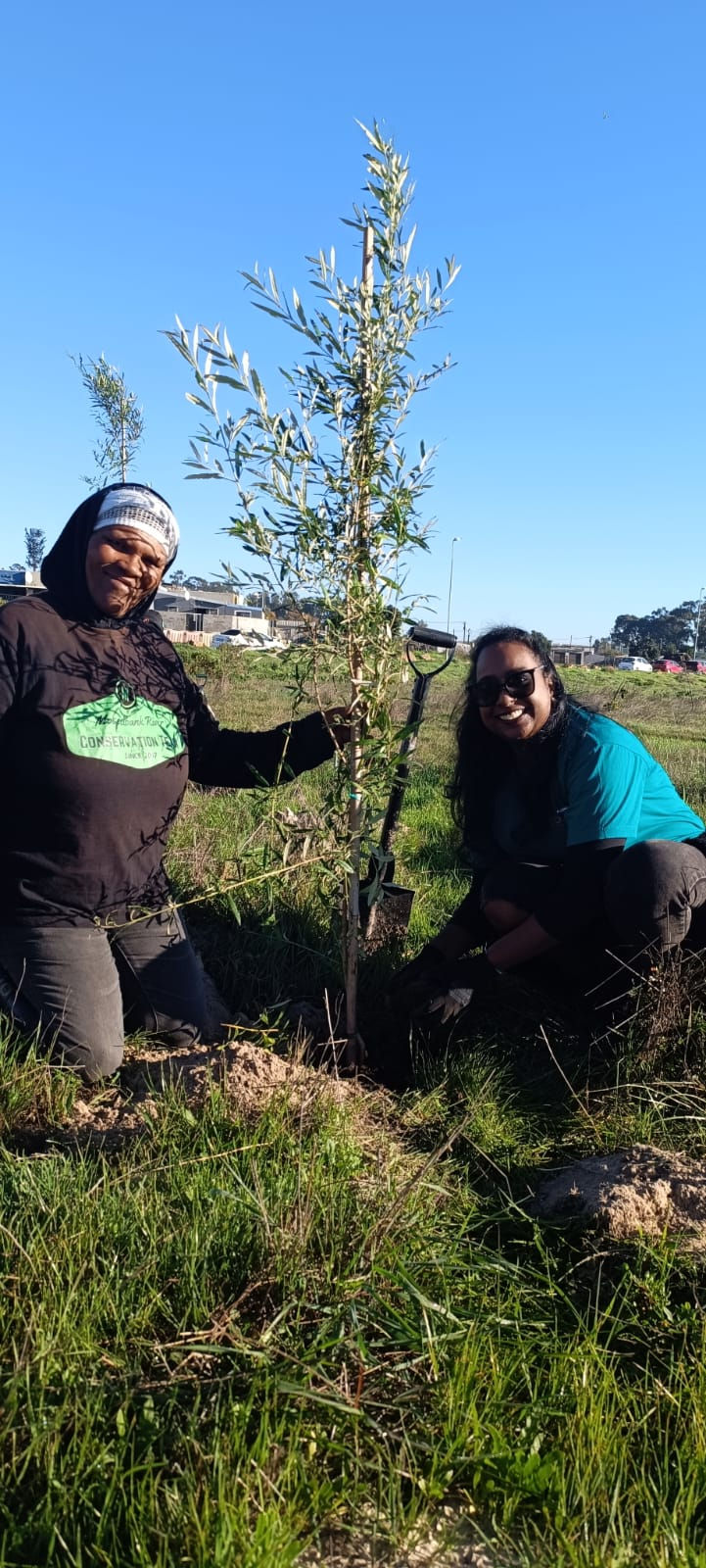 Sannie and Ackermans Team member showing tree they planted