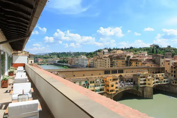 A stunning balcony view from Portrait Firenze overlooking the Arno River and the historic Ponte Vecchio in Florence, Italy.
