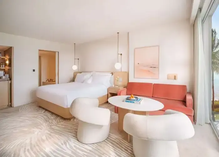 Modern, sunlit guest room at The Beach Club at The Boca Raton featuring elegant coastal décor, stylish furnishings, and large windows.