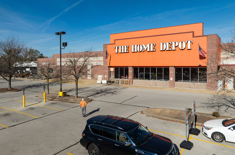 Aerial view of a freestanding big-box home improvement store with surface parking lot, garden center, and adjacent power center outparcels.