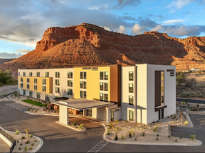 “SpringHill Suites hotel in Kanab, Utah, set against red rock cliffs at sunset.”