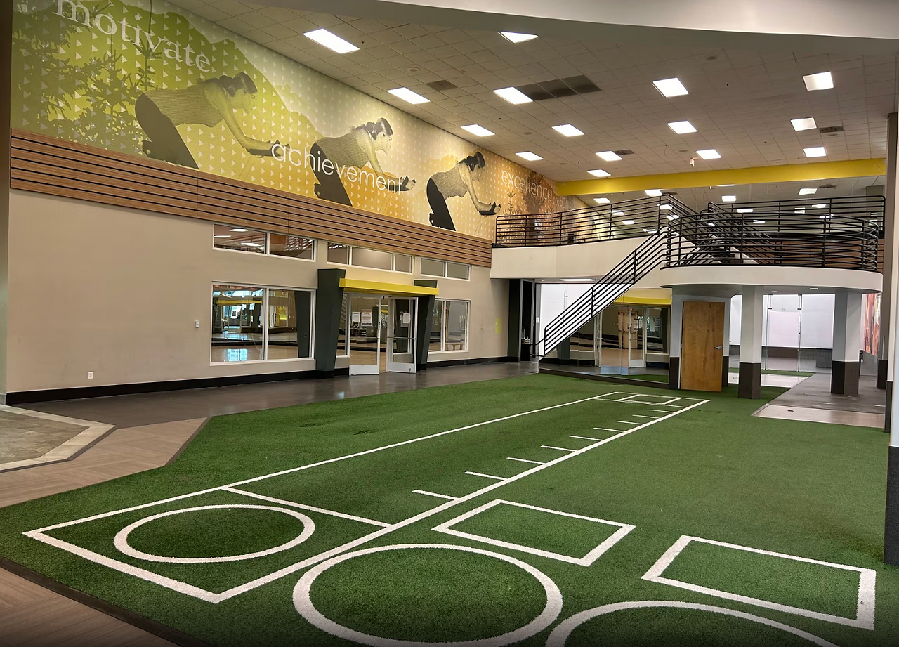 Interior of a modern U.S. fitness center with turf training area, motivational wall graphics, and mezzanine design, reflecting evolving trends in gym facility development and wellness investments across the 2025–2030 U.S. fitness industry outlook.