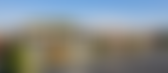 Commercial office building with surface parking lot showing striped accessible spaces, curb ramps, and pedestrian circulation routes — illustrating ADA compliance impact on site design and parking yield.