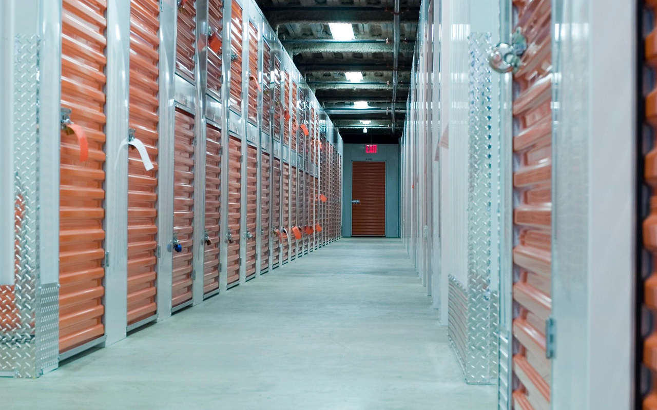 Interior corridor of a climate-controlled self-storage facility with rows of secured metal roll-up units — US self-storage occupancy and rent trends 2025.