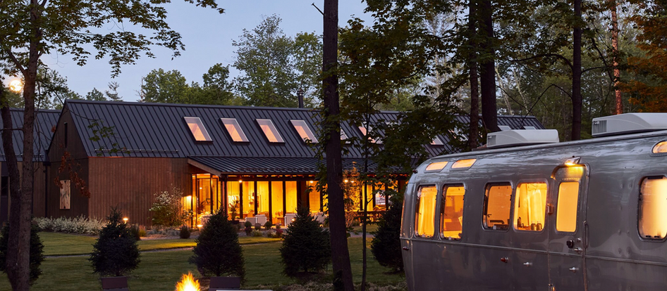 Airstream trailer and modern lodge at a luxury glamping resort at dusk, illustrating the mixed-structure capital investment common in SBA and USDA-financed outdoor hospitality developments.