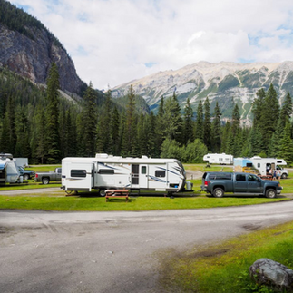 Scenic RV park with trailers surrounded by mountains and pine trees