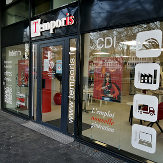 Vitrine d’agence avec adhésifs imprimés informatifs et pictogrammes sur surfaces vitrées.