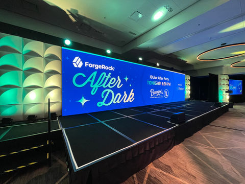 “Corporate afterparty stage setup with themed LED wall graphics, scenic lighting, and elevated performance platform.”