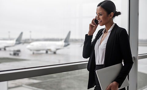 Work everywhere. Side view of young smiling woman is standing at airport lounge with lapto