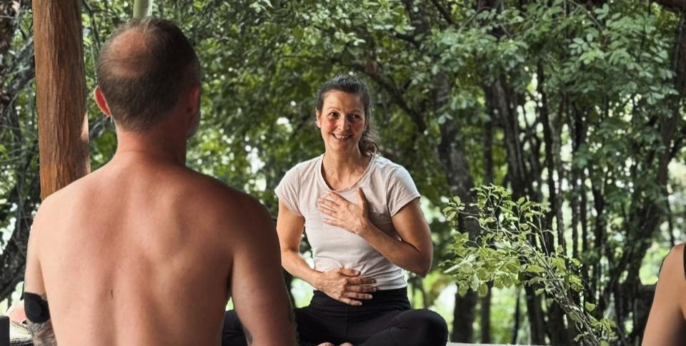 Close-up view of a yoga teacher guiding a student in a gentle pose outdoors