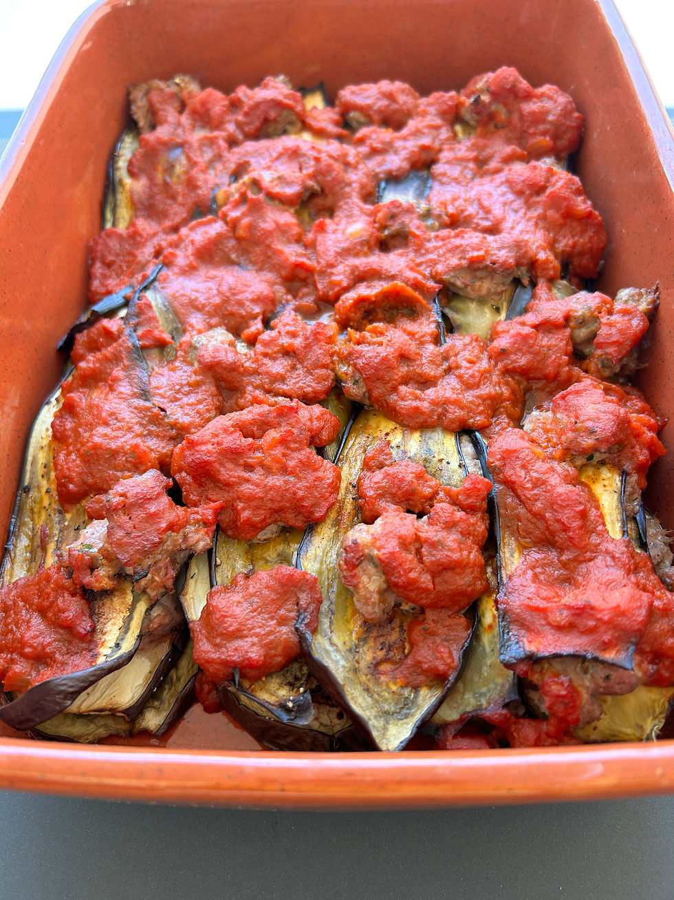 Tranches d'aubergines dorées et recouvertes de coulis de tomates dans un plat à gratin