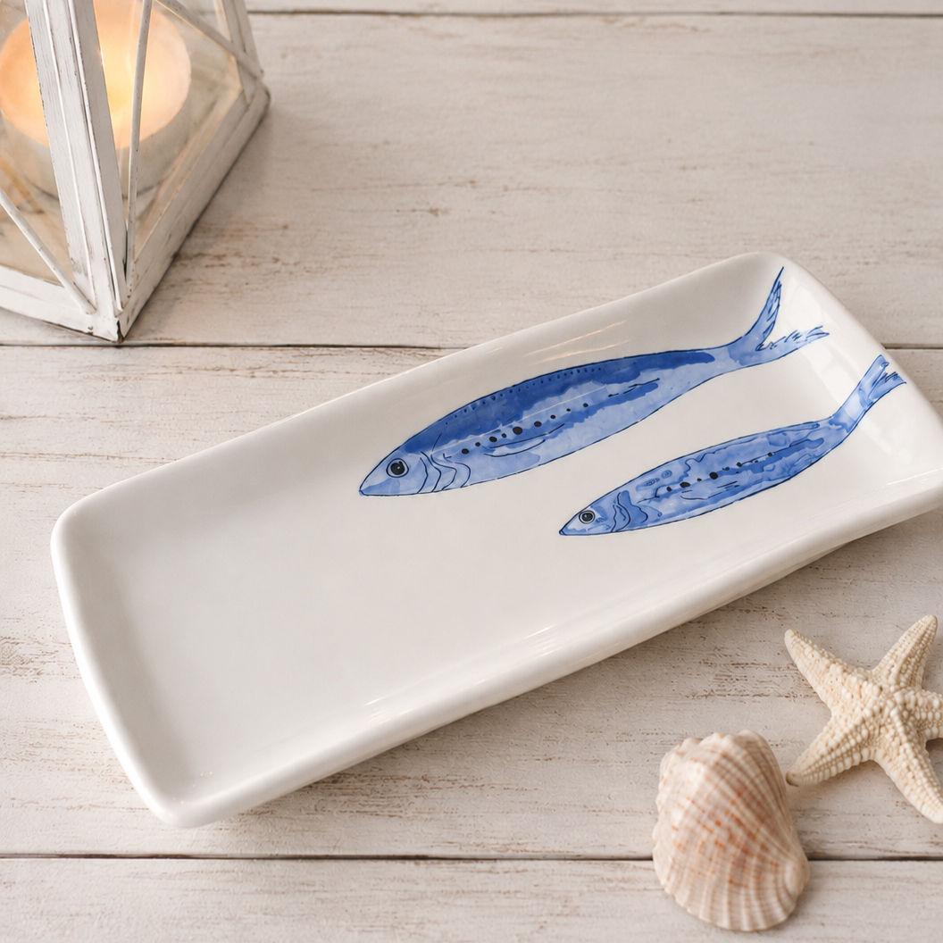 Coastal porcelain fish serving tray styled on a bright seaside dining table.