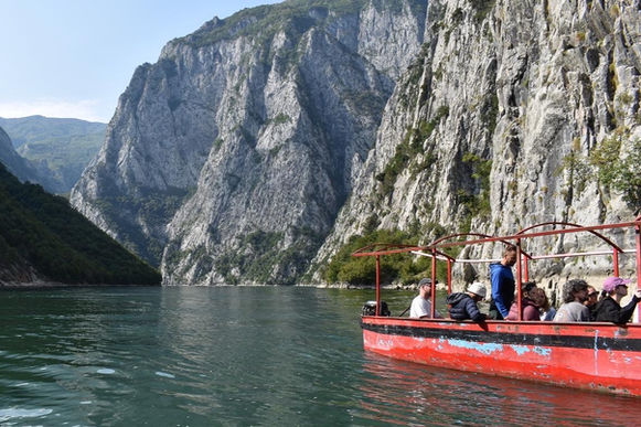 Red boat on a lake surrounded by tall, rocky mountains