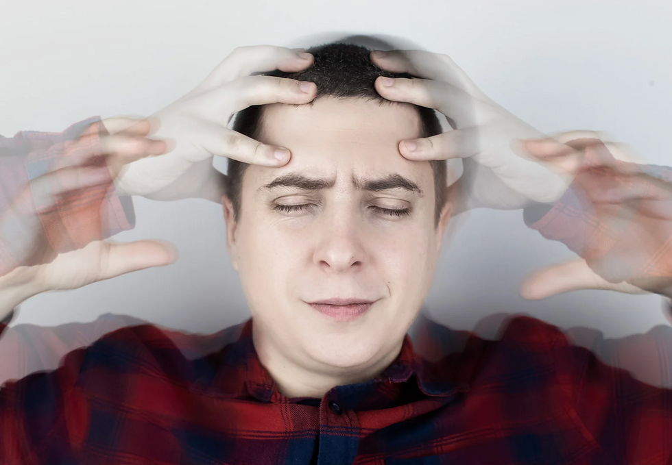 Man in red plaid shirt holding head with blurred hands, eyes closed, showing stress. White background.