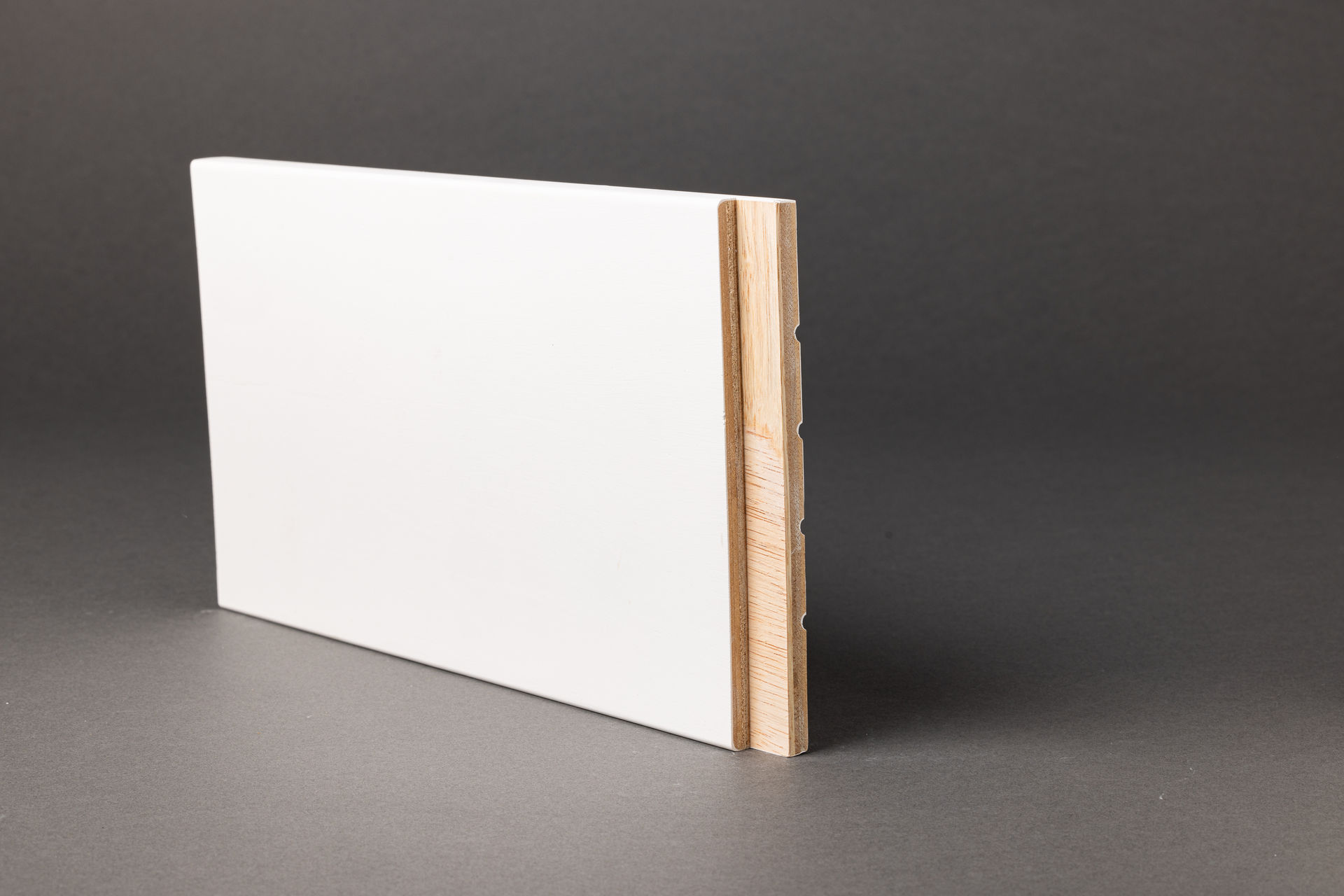 Side view of a white flat jamb with wood core visible, set against a gray background.