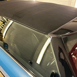 Blue convertible car with a clean, dark black soft top roof.