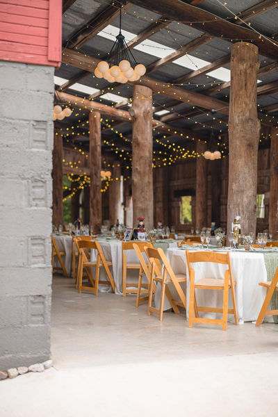 Wedding reception tables inside the Red Tail Farm barn with rustic wood beams and hanging lights.