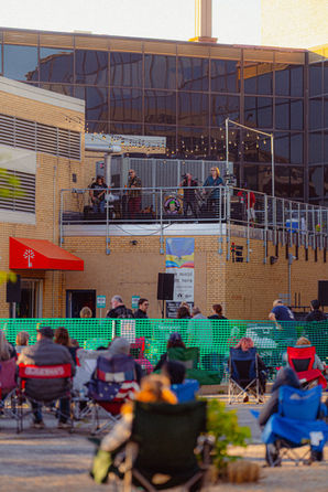 People sitting in lawn chairs watching a live band perform during Curbside Concerts outside the Elkhart Public Library in downtown Elkhart.